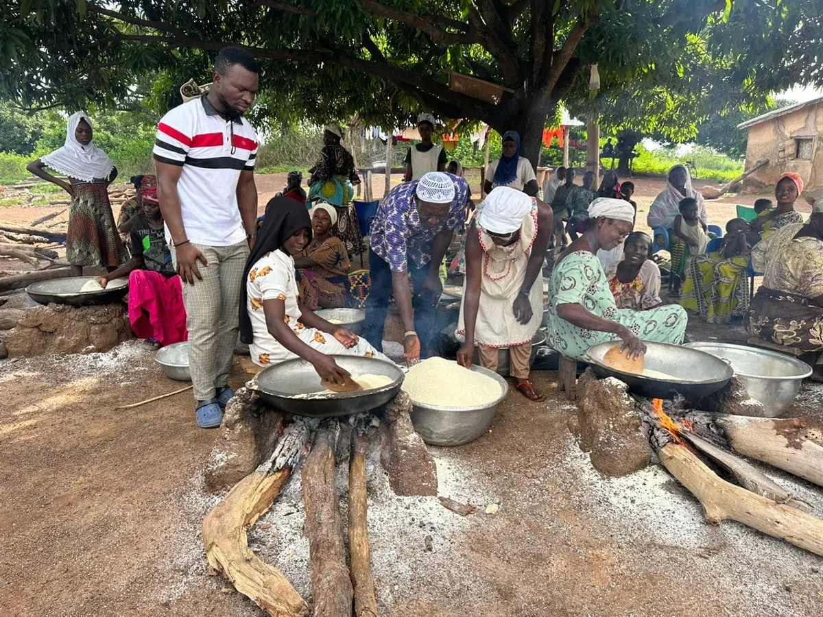 Members roasting gari together over open pans